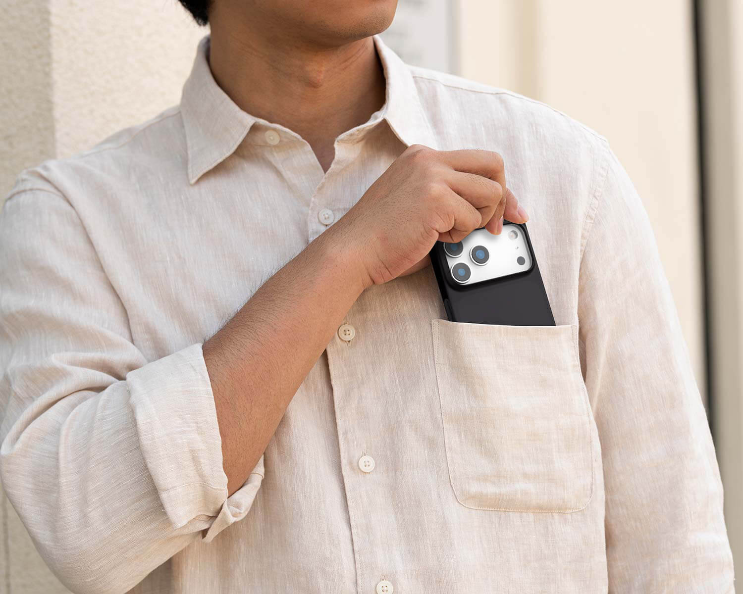 Person wearing a white shirt with a phone case attached to their shirt pocket.